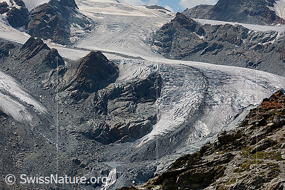 Photo: Tongue of the lower Theodul glacier. Approximately in the middle of the upper escarpment, a few longitudinal crevasses can be seen. The prominent medial moraine is more visible.