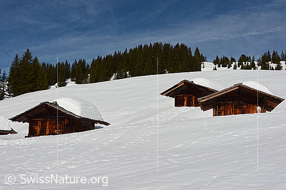 Foto: Alphütten in schneebedeckter Landschaft.