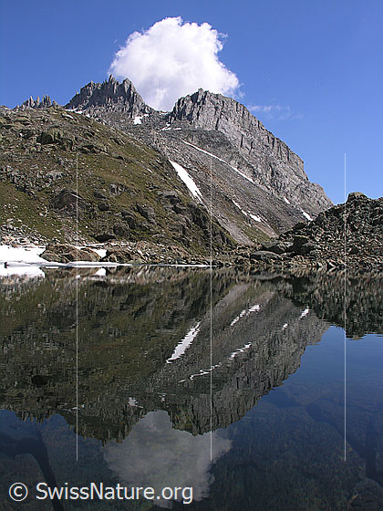 Foto: Grampielpass: Spiegelung eines Felsmassivs mit weisser Wolke im Grampielsee.