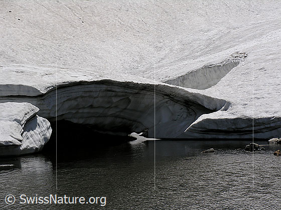 Foto: Kleiner Bergsee neben dem Fleschsee zum Teil mit Eis und Schnee bedeckt und Schneebrücke im Vordergrund.