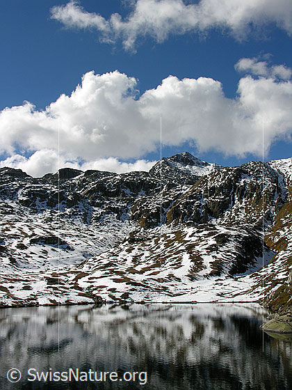 Foto: Wolken über dem Sidelhorn und Spiegelung der Schneeflecken im Totesee (Grimselpass).