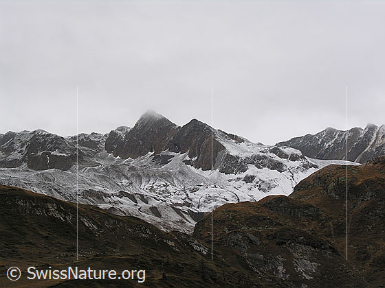 Foto: Blick vom Halsesee zum leicht verschneiten Turbhorn und Strahlgrät. Die Konturen des Geländes sind gut sichtbar. In tieferen Lagen kommt noch der Herbst zur Geltung.