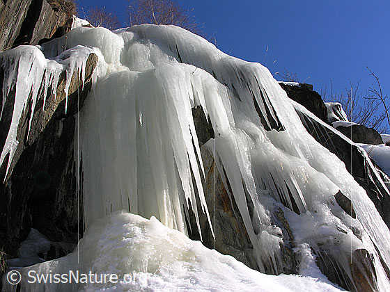 Foto: Grosse Eiszapfen hängen über eine Felsstufe. Eiszapfen verzaubern im Winter die Landschaft. Bei Tauwetter sind sie nicht ganz ungefährlich.