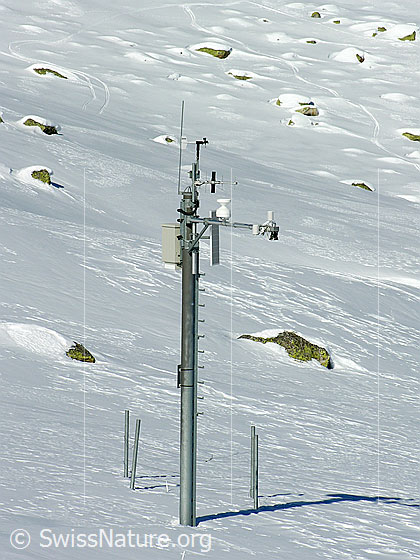 Foto: Meteomessstation in schneebedeckter Gebirgslandschaft.