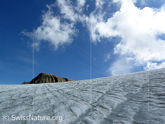 Foto: Jahrringe und Gletscherbäche auf dem Rappegletscher. Der Gipfel im Horizont ist das Rappehorn. Darüber steigen Quellwolken auf. Supraglaziale Entwässerung des Gletschers.