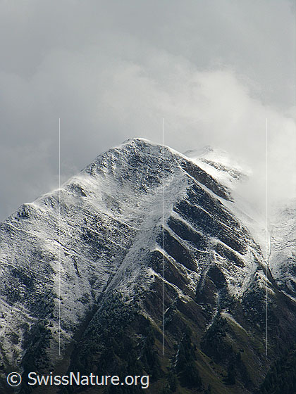 Foto: Berg mit deutlicher Schneefallgrenze. Nach einem kurzen Wintereinbruch reissen die Wolken auf und die Pyramide des Eggerhorns wird sichtbar. Die interessante Struktur im Fels wird durch die dünne Neuschneeschicht noch unterstrichen.