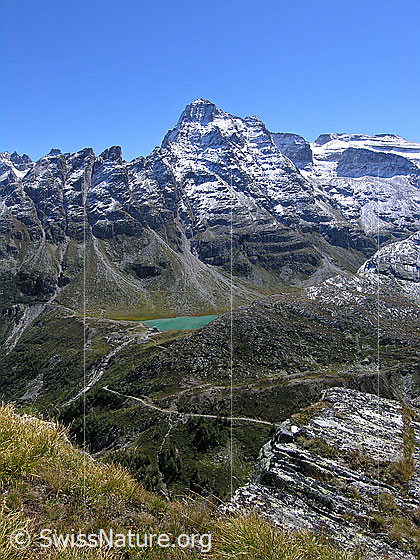 Foto: Tiefblick vom Sickeregale auf das Staubecken Chummibort mit seinem türkisfarbenen Wasser. Dahinter ist die markante Vordere Helse, vom Neuschnee schön gezeichnet, zu sehen.
