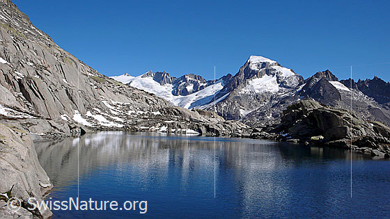 Foto: Blick über einen Bergsee mit schwacher Spiegelung zu Dammastock, Rhonestock, Tiefenstock, Galenstock, Sidelenhorn und Gross Furkahorn.