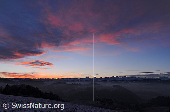 Foto: Morgenstimmung mit Morgenrot über dem Emmental. In den Tälern liegt Nebel und im Horizont ist die Bergkette der Berner Alpen zu sehen.