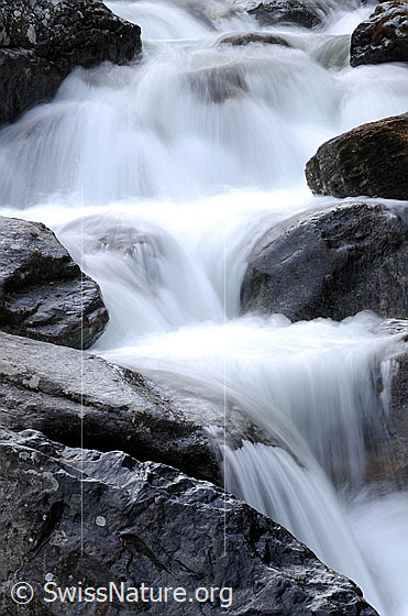 Foto: Wasserspiel um Felsblöcke in Bergbach (Langzeitbelichtung).