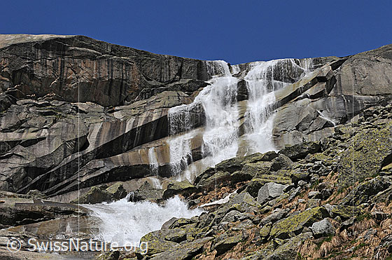 Foto: Wasserfälle ergiessen sich über eine gestufte Felswand. Die Felsen glänzen nass.