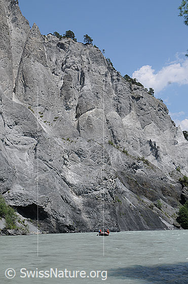 Foto: Türme in Felswand aus Kalkgestein in der Rheinschlucht. Auf dem Fluss (Vorderrhein) ist ein Schlauchboot zu  sehen.