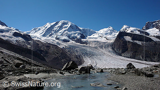 Foto: Gletscherbach vor Bergkulisse.
Gletscherbach am Rand des Gornergletschers. Im Hintergrund sind Grenzgletscher, Liskamm, Zwillingsgletscher, Castor und Pollux zu sehen..