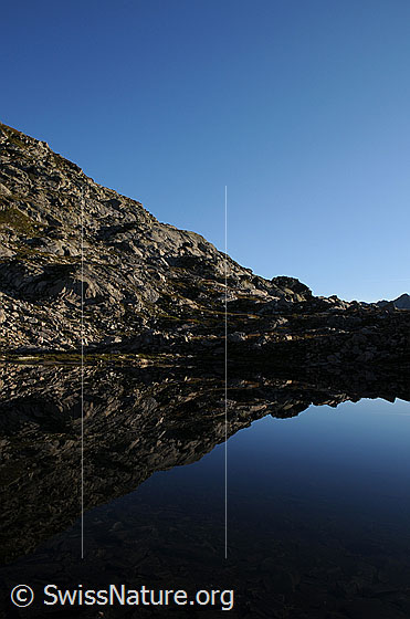 Foto: Spiegelung in Bergsee mit Morgenlicht.