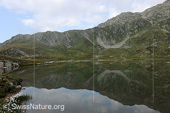 Foto: Spiegelnder Bergsee. Jostsee mit Spiegelung eines Bergrückens in der ruhigen Wasserfläche.