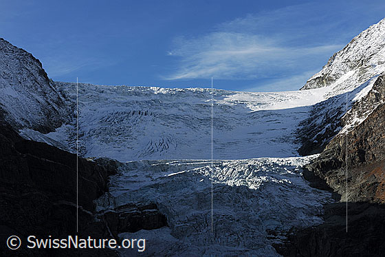 Foto: Turtmanngletscher mit Abbrüchen im Licht und Schatten. Am Gletscherrand sind Felsen zu sehen.