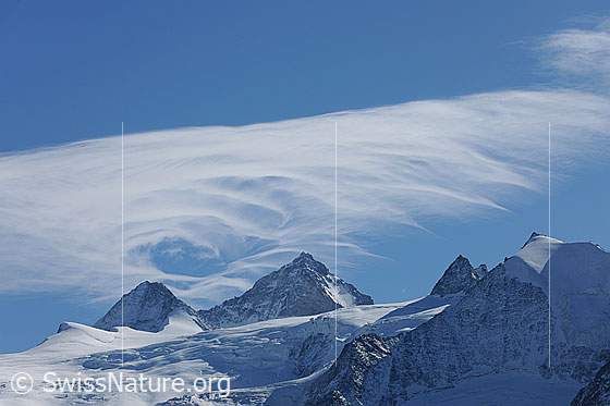 Foto: Grand Cornier und Dent Blanche mit interessant geformter Wolke am blauen Himmel. Davor der Glacier de Moiry, die Pointe de Bricola und die Pointes de Mourti.
