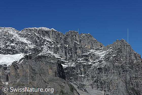Foto: Hörnli am Eiger. 
Felsgrat mit den Hörnli und Blick in die steil abfallenden Felswände. Auf den Felsstufen liegt etwas Neuschnee.