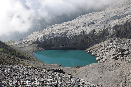 Foto: Bergsee: Lac de Ténéhet mit türkisfarbenem Wasser und Wolkenstimmung. Ein heller Felsriegel begrenzt die kleine Mulde, in welcher der See eingebettet liegt.